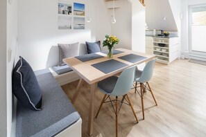 Ein moderner Essbereich mit einem Holztisch, grauen Stühlen und einer Bank mit Kissen.