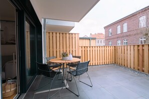 Eine Terrasse mit Tisch und Stühlen, ein Holzzaun und ein Gebäude im Hintergrund.