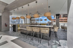 A modern bar area with wicker chairs, hanging lights, and a view of the cityscape. - Luxury E11EVEN Residence with ELITE AMENITIES (Miami)