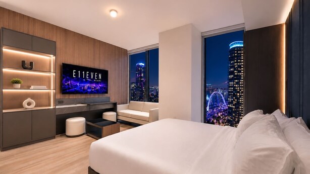 Une chambre d’hôtel moderne dotée d’un grand lit, d’une télévision, d’un bureau et offrant une vue sur la ville.