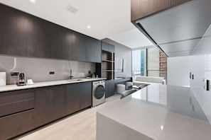 A modern kitchen with dark wood cabinets, a stainless steel range, and a built-in washing machine. - Luxury E11EVEN Residence with ELITE AMENITIES (Miami)