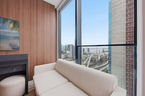 A modern room with a large window, a sofa, a small table, and a painting on the wall. - Luxury E11EVEN Residence with ELITE AMENITIES (Miami)