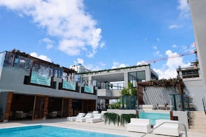 A modern hotel with a pool, outdoor seating, and a view of the city skyline. - Luxury E11EVEN Residence with ELITE AMENITIES (Miami)