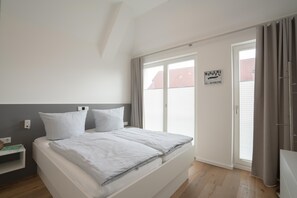 Ein Schlafzimmer mit einem Bett, einem Nachttisch, einem Fenster mit Vorhängen und einer Tür.