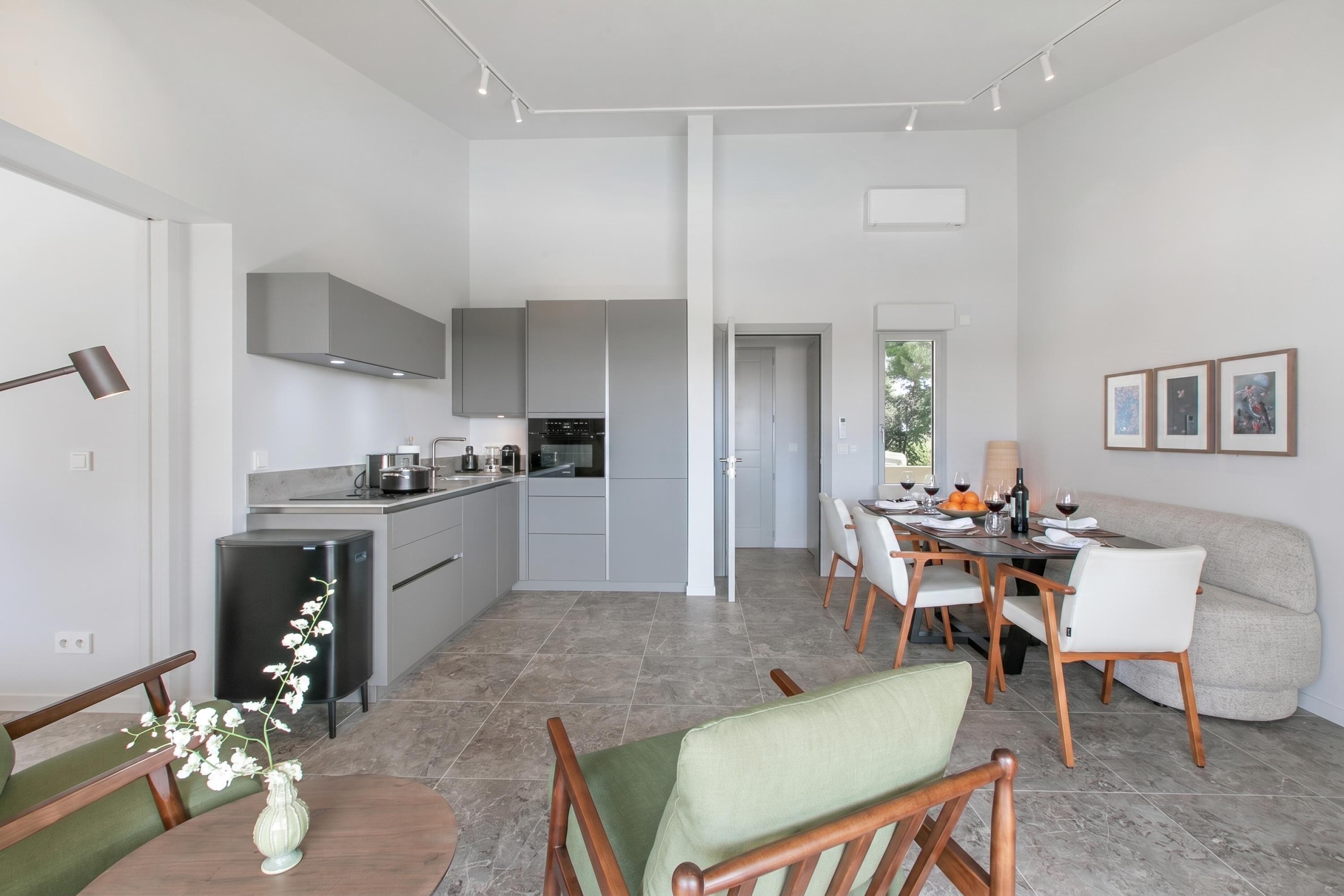 Eine moderne Küche mit integrierten Geräten, eine Essecke mit Tisch und Stühlen sowie eine Sitzecke mit einer Couch.