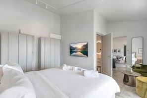 Ein modernes Hotelzimmer mit einem großen Bett, einem Flachbildfernseher, einem Gemälde und Blick auf den Speisesaal.