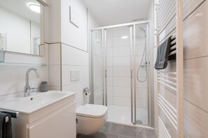 Ein modernes Badezimmer mit Duschkabine aus Glas, einem weißen Waschbecken und einer Toilette.