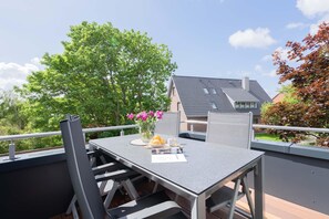 Ein Balkon mit Tisch, Stühlen und einem Blumenstrauß.