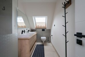 Ein modernes Badezimmer mit einem Holzlagerfeld, einem weißen Waschbecken, einer Toilette und einem Fenster über der Toilette.