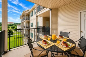 A balcony with a table set for breakfast, overlooking a residential area. - Branson Condo with Golf Course View • 3 King Suites • Sleeps 6 (Branson)