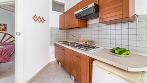 A compact kitchen with wooden cabinets, a gas stove, and a tiled backsplash. - Leuca Relax&Sea n.1bbis, Castrignano del Capo, Italy (Castrignano del Capo)