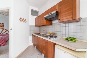 A compact kitchen with wooden cabinets, a gas stove, and a tiled backsplash. - Leuca Relax&Sea n.1bbis, Castrignano del Capo, Italy (Castrignano del Capo)