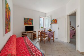 A room with a bed, a desk with a computer, a dining table with chairs, and a door leading to another room. - Leuca Relax&Sea n.1bbis, Castrignano del Capo, Italy (Castrignano del Capo)