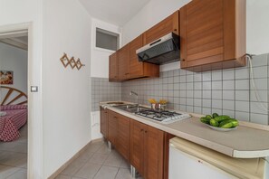 A compact kitchen with wooden cabinets, a gas stove, and a tiled backsplash. - Leuca Relax&Sea n.1bbis, Castrignano del Capo, Italy (Castrignano del Capo)