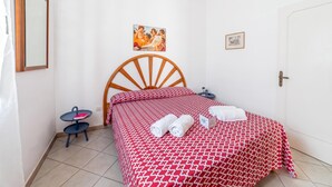 A bedroom with a wooden bed, a small bedside table, a chair, and a wall-mounted picture. - Leuca Relax&Sea n.1bbis, Castrignano del Capo, Italy (Castrignano del Capo)