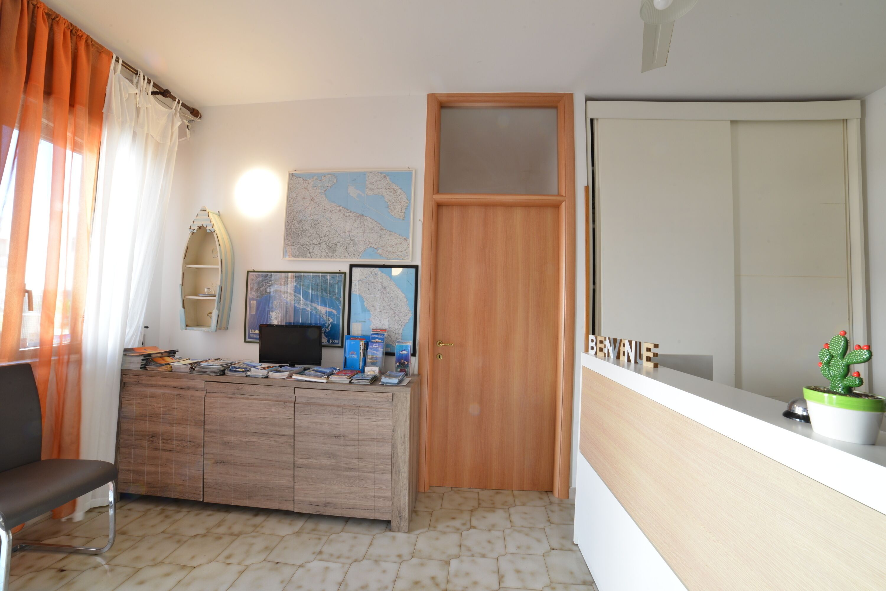 Una habitación con un escritorio de madera, una silla, un mapa y un cactus en el alféizar de la ventana.