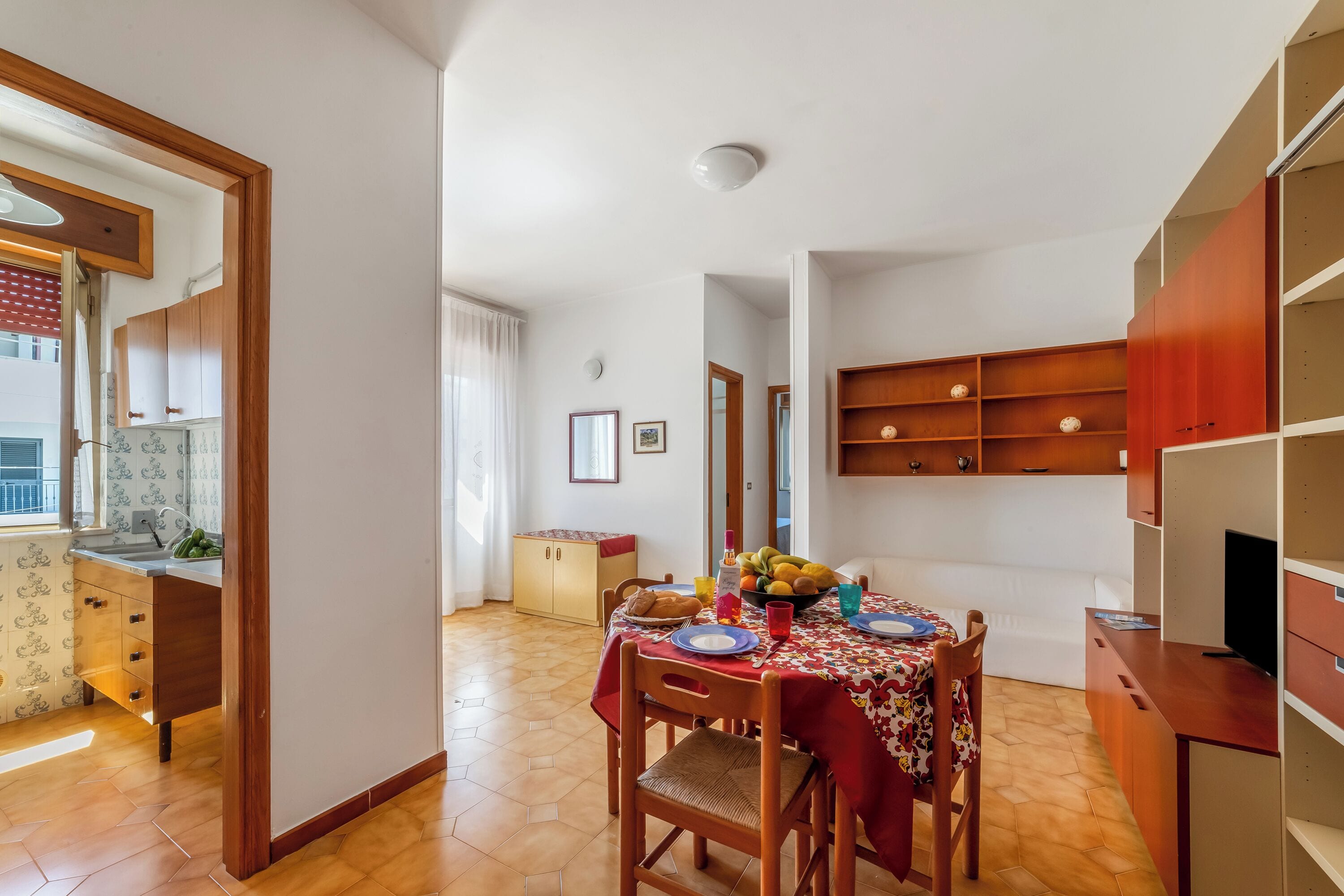 A compact living space with a dining area, kitchenette, and a TV.
