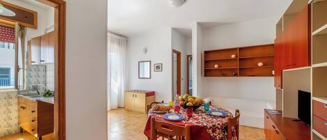 A compact living space with a dining area, kitchenette, and a TV.