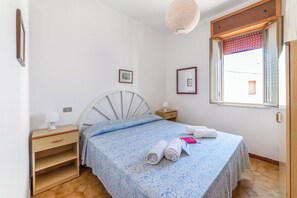 A bedroom with a bed, bedside tables, a window with blinds, and a hanging light fixture. - Leuca Relax&Sea n.8C, Castrignano del Capo, Italy (Castrignano del Capo)