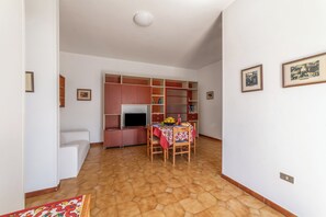 A room with a dining table, chairs, a television, and a bookshelf. - Leuca Relax&Sea n.8C, Castrignano del Capo, Italy (Castrignano del Capo)