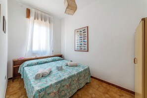 A bedroom with two beds, a wooden headboard, a framed poster on the wall, and a wooden floor. - Leuca Relax&Sea n.8C, Castrignano del Capo, Italy (Castrignano del Capo)