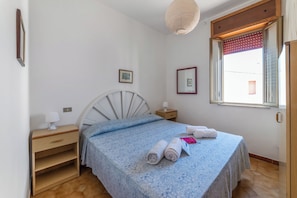 A bedroom with a bed, bedside tables, a nightstand, a lamp, a window with a view, and a hanging light fixture. - Leuca Relax&Sea n.8C, Castrignano del Capo, Italy (Castrignano del Capo)