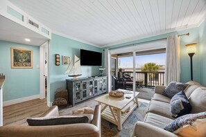 A living room with a sofa, chairs, a table, a television, and a view of the outdoors. - Partial Ocean-view condo with 2 bedrooms, perfect for a beach getaway (Fernandina Beach)