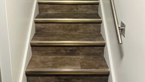 A staircase with a handrail, leading to a room with a dark wall and a blue accent. -     The Pinery | Modern Retreat with Pool & Family-Friendly Comfort (St. Catharines)