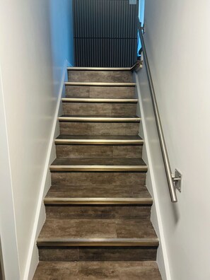 A staircase with a handrail, leading to a room with a dark wall and a blue accent.