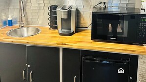 A kitchen with a sink, coffee maker, microwave, cabinets, and a tiled backsplash. -     The Pinery | Modern Retreat with Pool & Family-Friendly Comfort (St. Catharines)