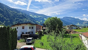 Ein Wohngebiet mit Häusern, einem Auto und Bergen im Hintergrund.