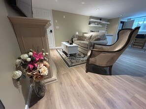 A living room with a sofa, a coffee table, a decorative vase with flowers, and a patterned rug. - Stay on Beautiful Glen Lake Victoria (Victoria)
