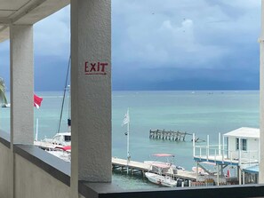 A view of a marina with boats docked, a pier extending into the water, and an exit sign on a column.