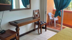 A room with a bed, a desk, a chair, a TV, and a sliding glass door with curtains.