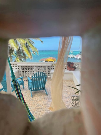 A balcony with a view of the ocean, a hammock, and blue chairs.. Hotel Spindrift & Golf Cart Rental