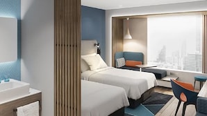 Quarto de hotel moderno com duas camas, vista para a cidade, uma mesa de trabalho e banheiro com pia e espelho.