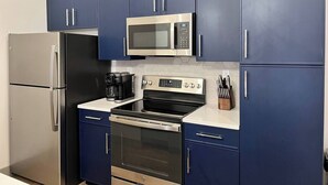 A kitchen with stainless steel appliances, including a microwave, oven, and refrigerator, with blue cabinets and a white countertop. - Brick & Bed, Modern Loft, Walk to Arch, Stadium, 402 (St. Louis)