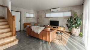 A modern living room with a sofa, TV, and large windows.