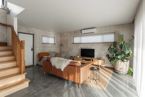 A modern living room with a sofa, TV, and large windows. - A unique, luxurious, eco-friendly hempcrete home on Bruny Island. Pet friendly! (Alonnah)