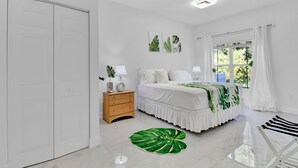 Um quarto com cama, mesa de cabeceira e janela com cortinas.