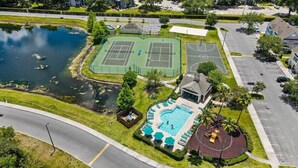Vista aérea de uma área residencial com quadra de tênis, piscina e estrada.