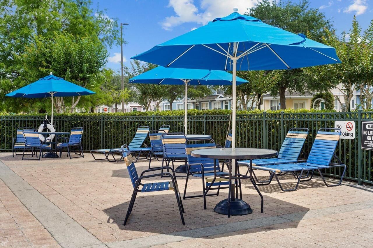 Outdoor seating with blue umbrellas, a round table, and lounge chairs.