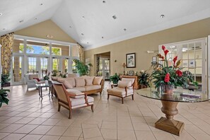 Eine geräumige Lobby mit hoher Decke, großen Fenstern und verschiedenen Sitzgelegenheiten, darunter Sofas und Sessel.