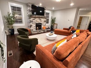 Ein Wohnzimmer mit Kamin aus Stein, einem großen Flachbildfernseher und einem Ecksofa.