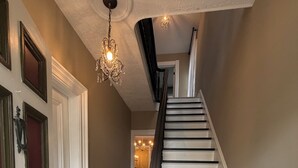 A staircase with white steps and dark railings, leading to a room with a chandelier. - Victorian home 7-bedroom homes with full mother on law suite in back (La Porte)