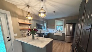 A modern kitchen with a marble island, stainless steel appliances, pendant lighting, and a view to the outdoors. - Victorian home 7-bedroom homes with full mother on law suite in back (La Porte)