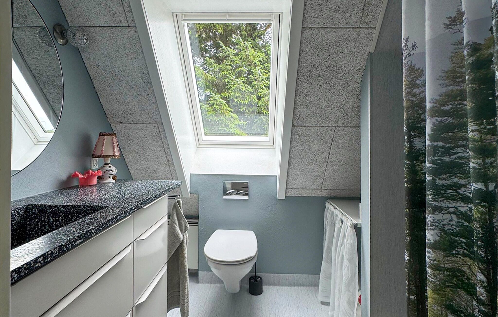 A compact bathroom with a window, a toilet, and a sink.