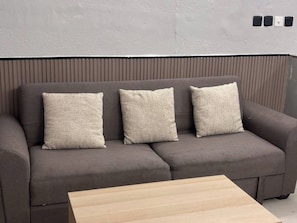 A grey sofa with three cushions and a wooden coffee table.