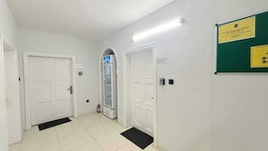 A hallway with white doors, a refrigerator, and a green signboard.