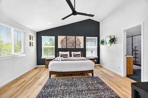 A bedroom with a bed, a ceiling fan, a large window with blinds, and artwork on the wall. - 4BR Mountain Retreat with Games, Large Deck &Views (Colorado Springs)